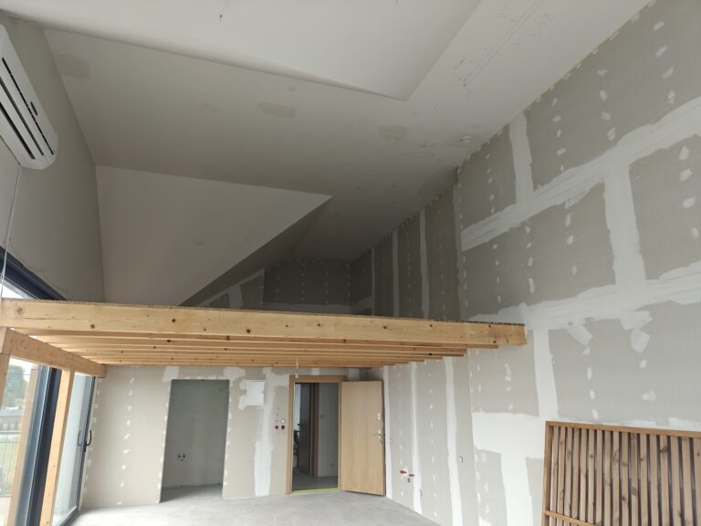 Wysoki sufit i antresola w mieszkaniu w stanie deweloperskim podczas odbioru technicznego – sprawdzanie jakości wykonania ścian i sufitów.